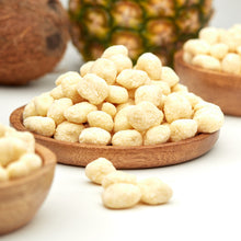 Ananasstücke in weißer Schokolade und Kokos von NESSLIM, serviert in einer Holzschale mit frischer Ananas und Kokosnuss.