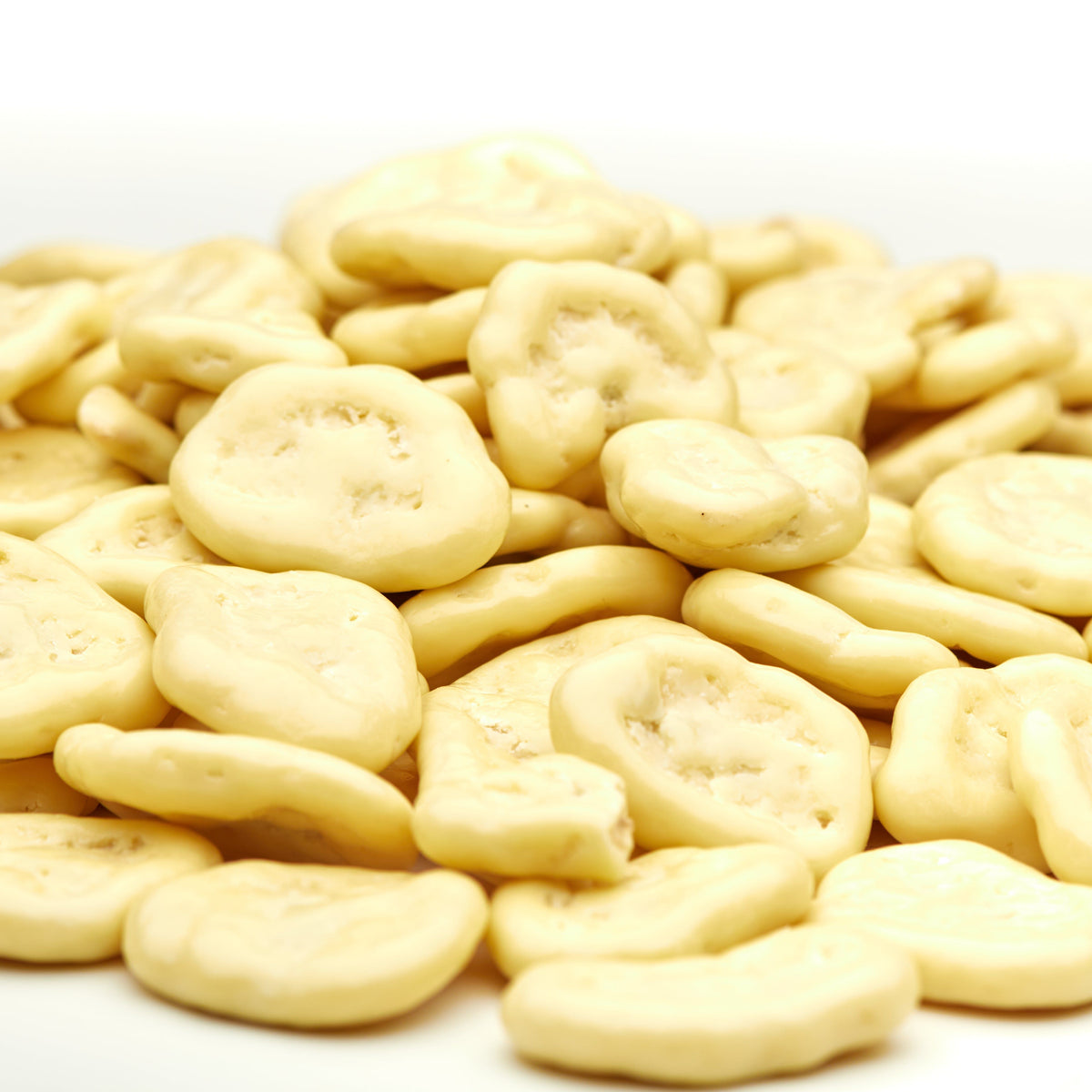 Makroaufnahme weißer Schoko-Bananenchips von NESSLIM mit sichtbarer Bananenscheibe und zarter Schokoladenhülle.