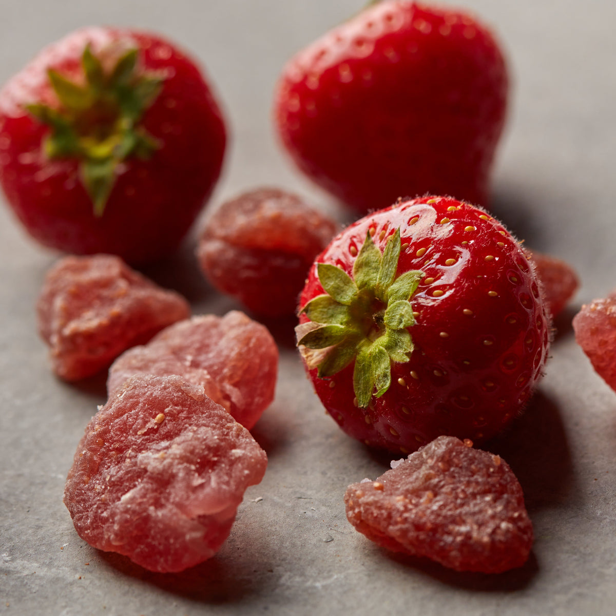 Kandierte Erdbeeren von NESSLIM mit frischen Erdbeeren auf grauer Marmorplatte zum Backen und für Dessertgläser.