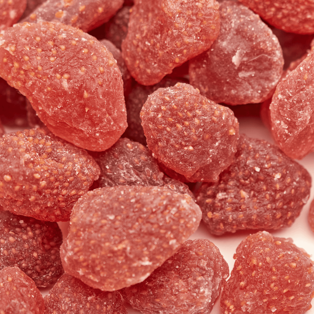Makroaufnahme kandierter Erdbeerstücke von NESSLIM mit sichtbaren Samen und zarter, leicht chewy Fruchtstruktur.