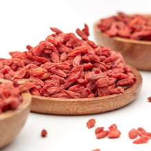 Getrocknete Goji Beeren von NESSLIM auf einem Holzteller, mit kleinen roten Beeren und natürlich runzliger Oberfläche.