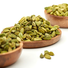 Ganzer grüner Kardamom von Nesslim mit aromatischen Kardamomkapseln in Holzschalen und einzelnen Kapseln im Vordergrund