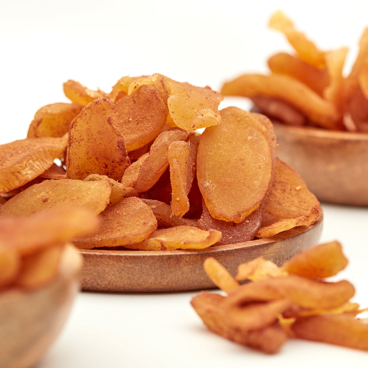 Kandierte Ingwerscheiben mit Zimt von NESSLIM in Holzschalen als süß-scharfer Snack zur Teezeit und für gemütliche Genussmomente.