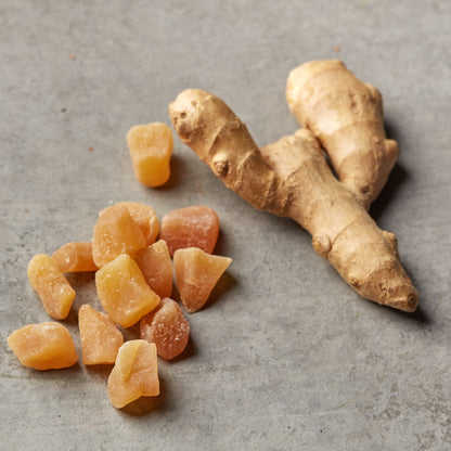 Mild kandierte Ingwerstücke von NESSLIM auf grauer Marmorplatte als kleiner Snack zur Teezeit.