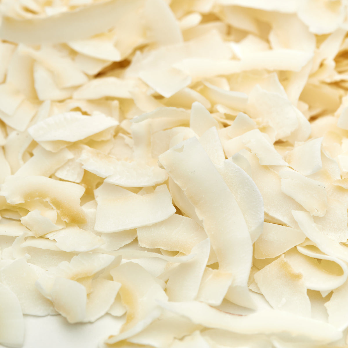Makroaufnahme naturbelassener Kokosnuss-Chips von NESSLIM mit dünner, knuspriger Struktur und mildem Kokosgeschmack.