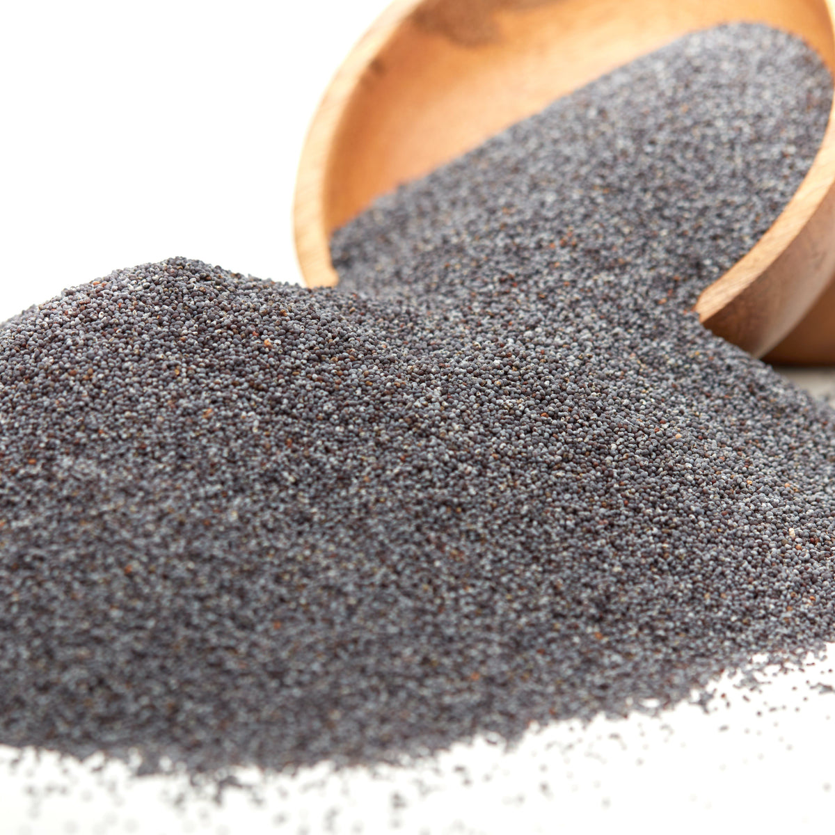 Naturbelassene Blaumohn-Mohnsaat von Nesslim als großer Produkthaufen mit ausgeschütteten Mohnsamen