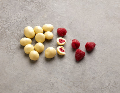 Geöffnete NESSLIM Packung mit Himbeeren in weißer Schokolade