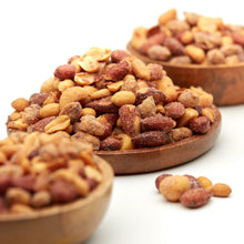 Rauchig gewürzter Nussmix Smokehouse von NESSLIM mit Erdnüssen, Mandeln, Cashews und Macadamias auf einem Holzteller.