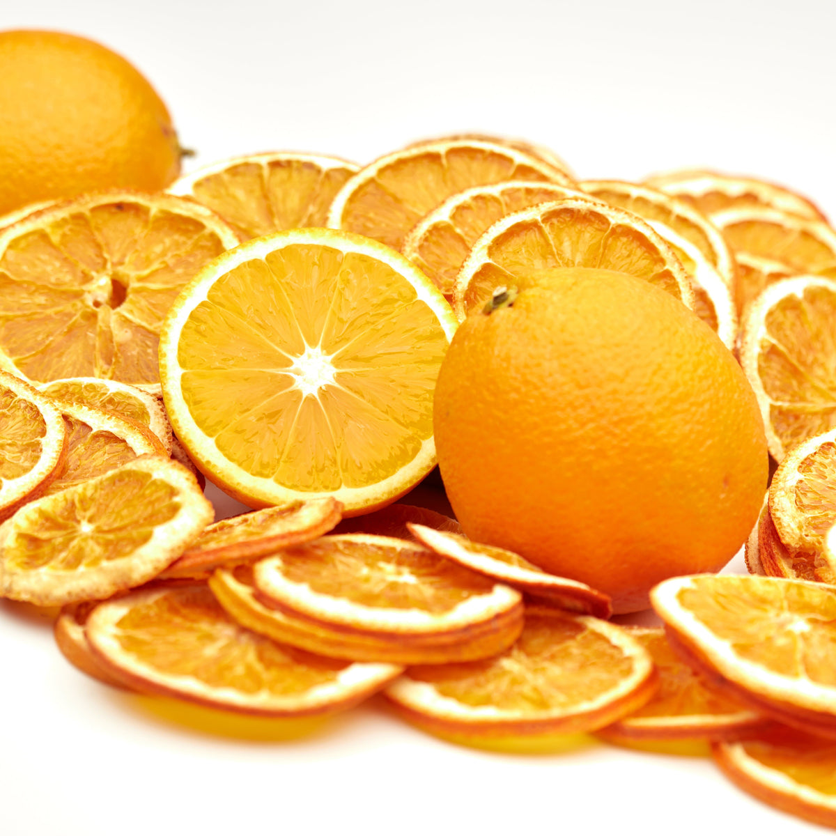 Getrocknete Orangenscheiben von NESSLIM neben frischen Orangen als Garnish für Cocktails, Mocktails und Spritz-Getränke.