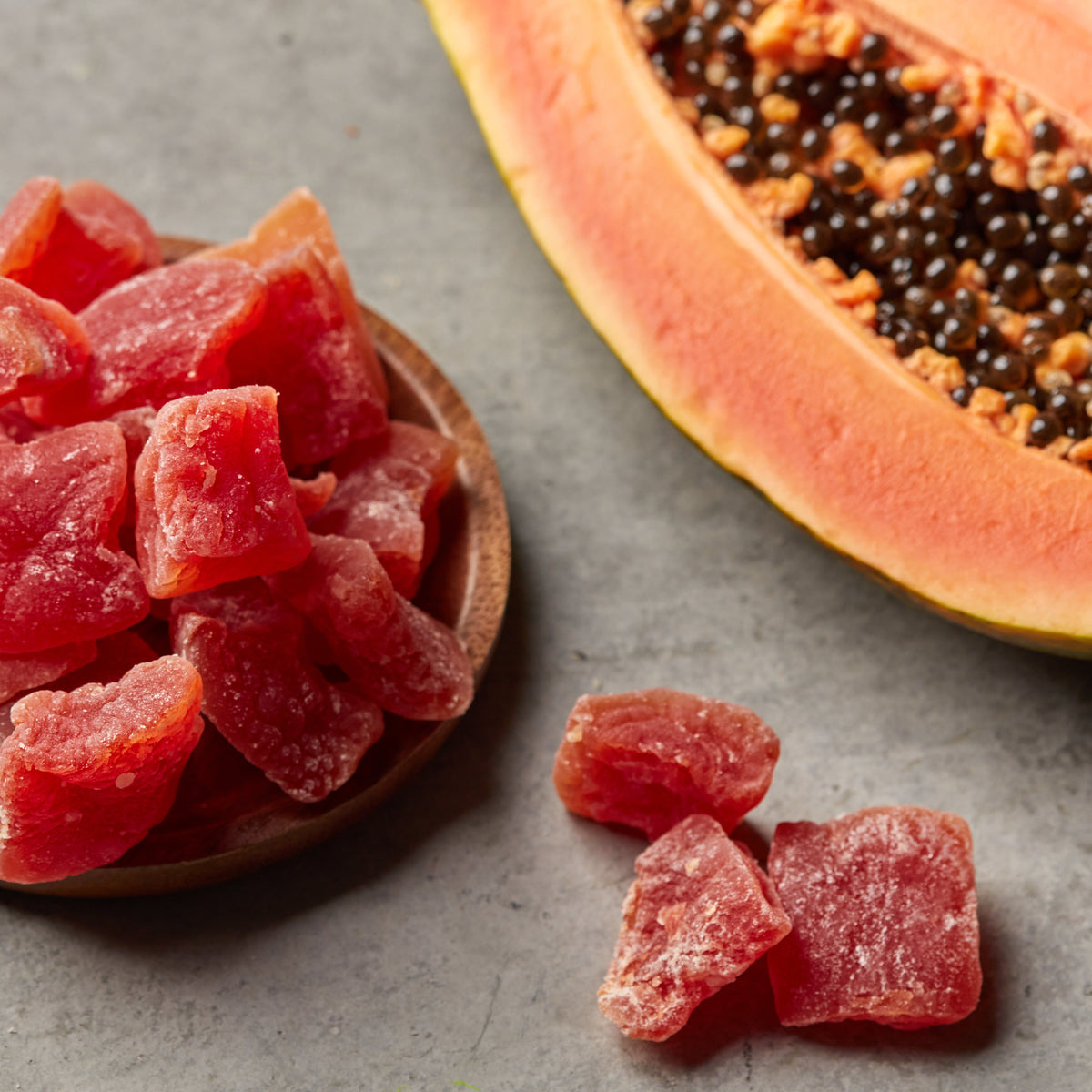 Papaya Chunks von Nesslim mit frischer Papaya als exotischer Trockenfrucht Snack auf grauem Untergrund
