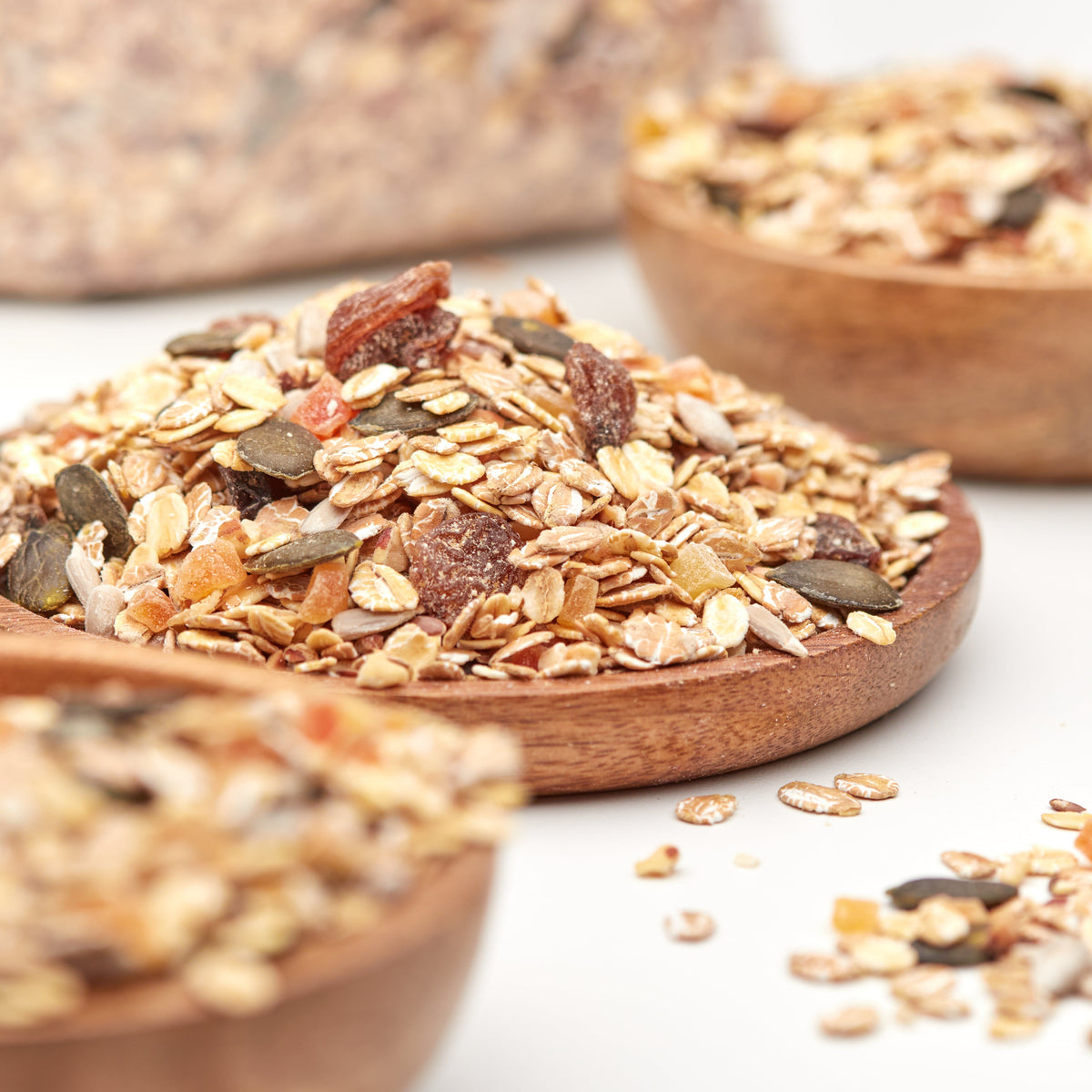 Nesslim Premium Müsli mit knusprigen Flocken, Nüssen, Kernen und Trockenfrüchten auf einem Holzteller.