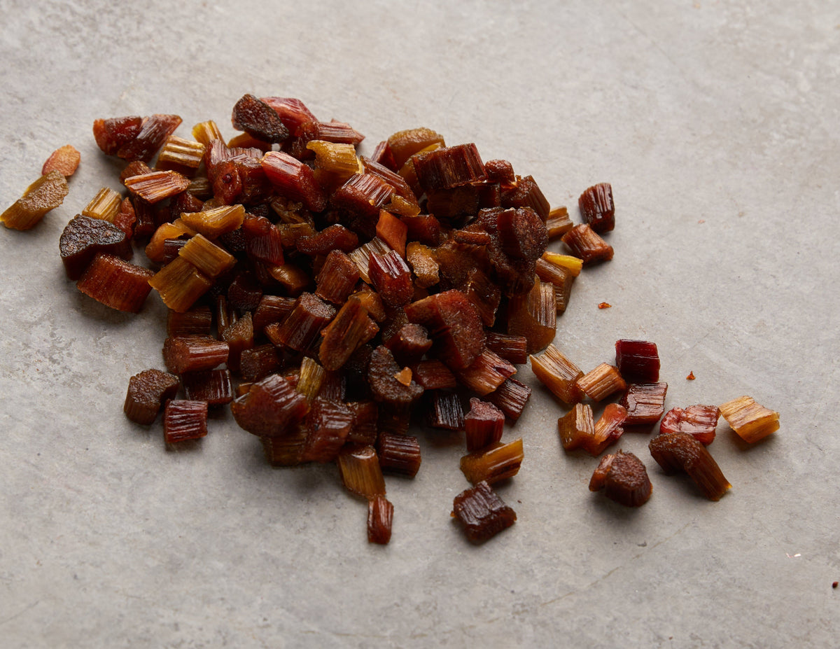 Rhabarber Chunks von NESSLIM auf grauer Marmorplatte als aromatische Zutat für Snack-Mixe und kreative Küche.