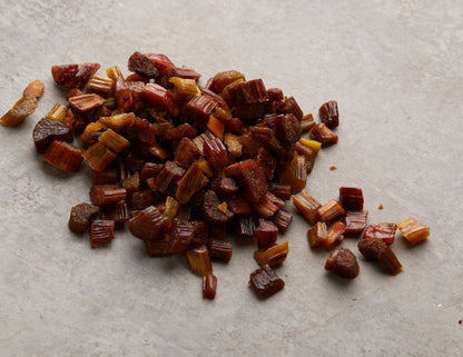 Rhabarber Chunks von NESSLIM auf grauer Marmorplatte als aromatische Zutat für Snack-Mixe und kreative Küche.