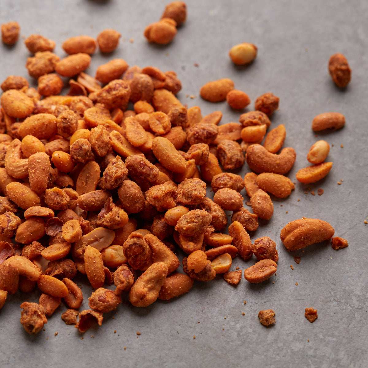 Scharfer Nussmix mit Erdnüssen und Cashewkernen von NESSLIM auf grauer Steinplatte.