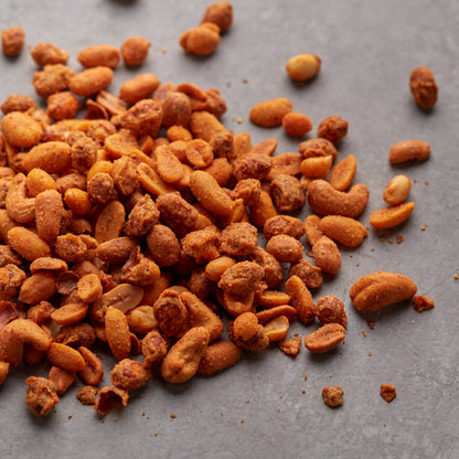 Scharfer Nussmix mit Erdnüssen und Cashewkernen von NESSLIM auf grauer Steinplatte.