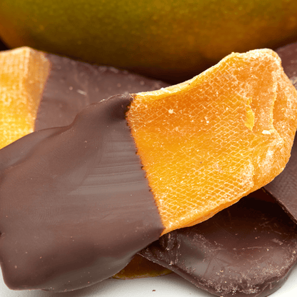 Makroaufnahme eines getrockneten Mangostreifens mit dunkler Schokoglasur und sichtbarer fruchtiger Mango-Struktur.