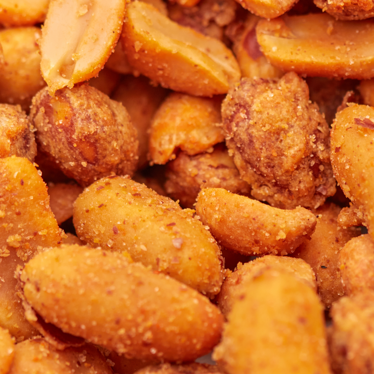 Makroaufnahme des Nussmix Spicy Chili mit sichtbarer Chili-Würzung auf Erdnüssen und Cashewkernen.