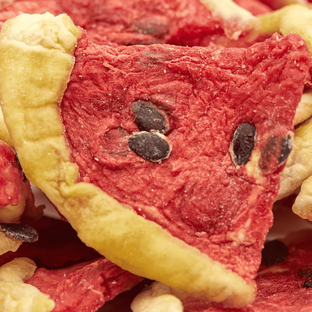 Makroaufnahme eines getrockneten Wassermelonenstücks im Pizzacut mit sichtbaren schwarzen Kernen.